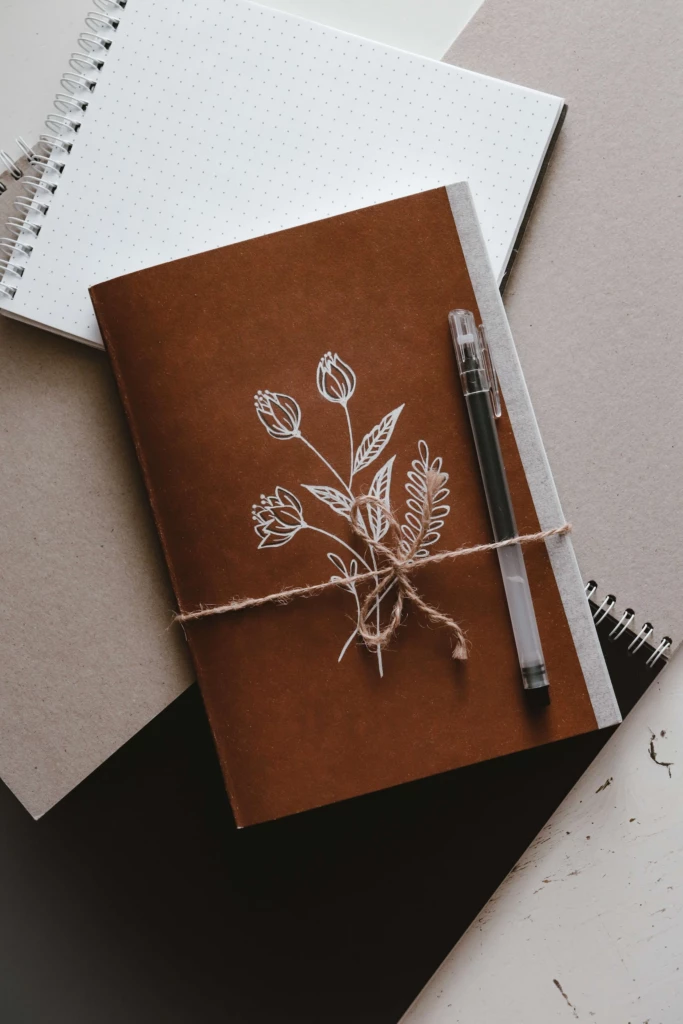 Brun anteckningsbok med en vit blomma tryckt på framsidan